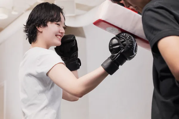 トレーナーの構えるミットにパンチを打つ会員
